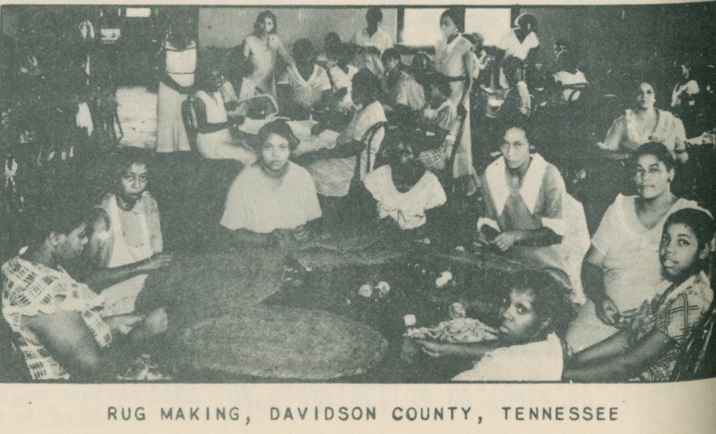 Black and white photograph of a large group of women of color making rugs by hand.