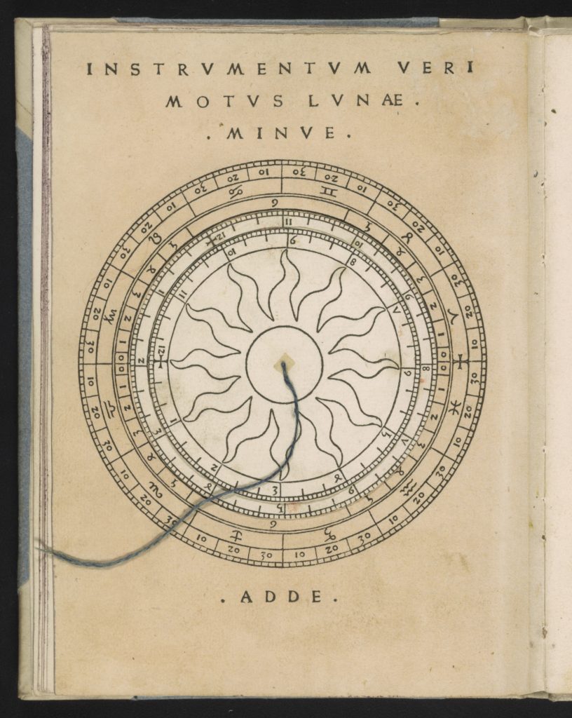Image of a page of a book with a large circle printed on it with the signs of the zodiac and other notations. Stacked on top of this circle are two smaller movable dials, both of which also have notations and units of measurement around their edges. The center of the topmost dial is decorated with a sun.