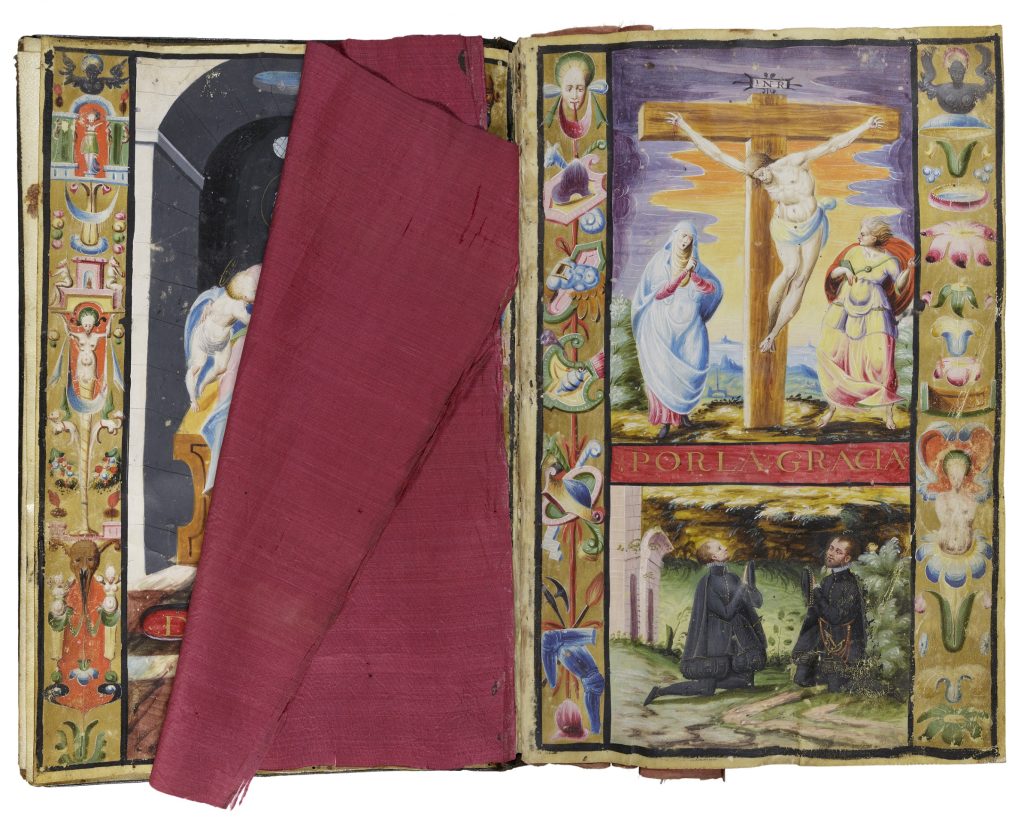 Two-page spread of an open book. On the right-hand page is an illumination of two white men kneeling in a garden. They look up to the image above them, which shows Jesus being crucified. On the left-hand side of the cross is a woman wearing a blue robe. On the right is figure wearing colorful robes and a red cape. All three figures are white. Both images are bordered on the left and right with small images. The page on the left is partly covered by square of red silk, revealing a border of small images and part of a painted arch.