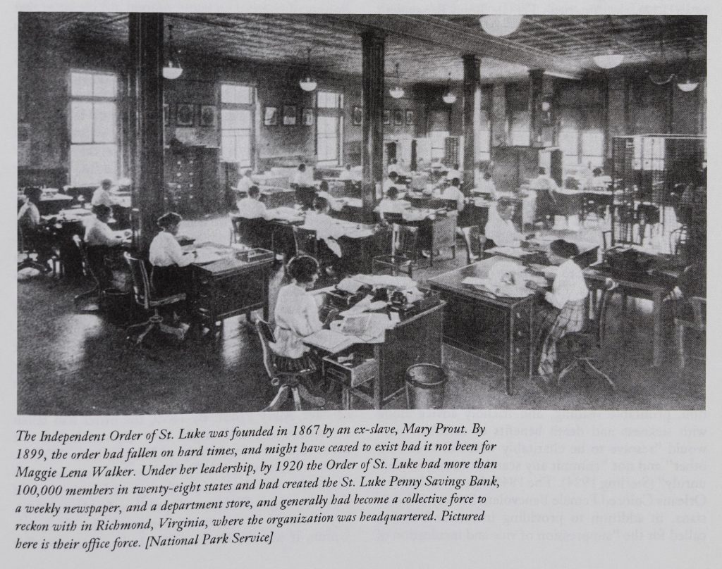 Black and white photograph of a large room filled with Black women working at desks covered in paper and typewriters. The caption under the photograph reads, "The Independent Order of St. Luke was founded in 1867 by an ex-slave, Mary Prout. By 1899, the order had fallen on hard times, and might have ceased to exist had it not been for Maggie Lena Walker. Under her leadership, by 1920 the Order of St. Luke had been more than 100,000 members in twenty-eight states and had created the St. Luke Penny Savings Bank, a weekly newspaper, and a department store, and generally had become a collective force to reckon with in Richmond, Virginia, where the organization was headquartered. Pictured here is their office force. [National Park Service]."