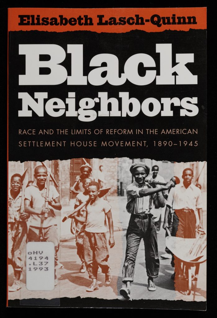 Cover of the book Black Neighbors. The title is in red on a black background above a black and white photograph of a group of Black boys carrying shovels with one pushing a wheelbarrow.