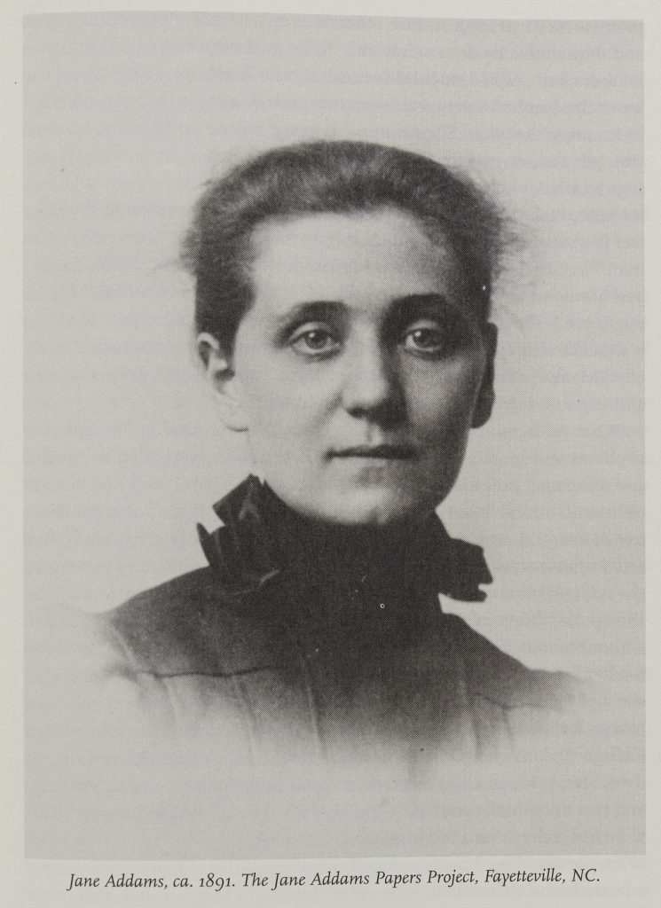 Black-and-white photo of a white woman shown from the shoulders up. She looks into the camera and wears a high-collared dark dress and her hair pulled up. The photo is captioned, "Jane Addams, ca. 1891. The James Addams Papers Project, Fayetteville, NC."