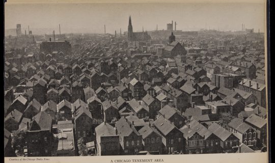 Elevated view of a city neighborhood showing rows of tightly packed two-and-three story houses with a church and many industrial smoke stacks on the horizon.