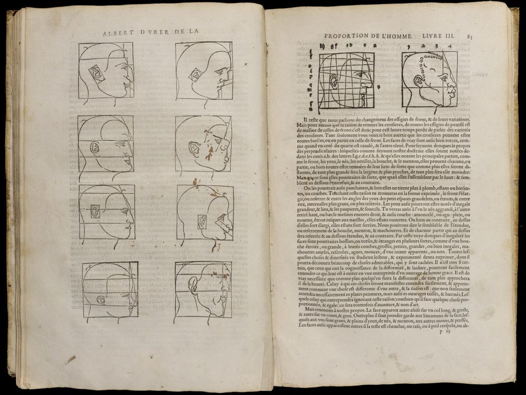 Two page spread of an early printed book. On the left Page are diagrams of six human heads in profile. Each head has different shaped features and is in a box with lines and squares highlighting the angles and proportions of their different features. On the right are two more heads and text in French.