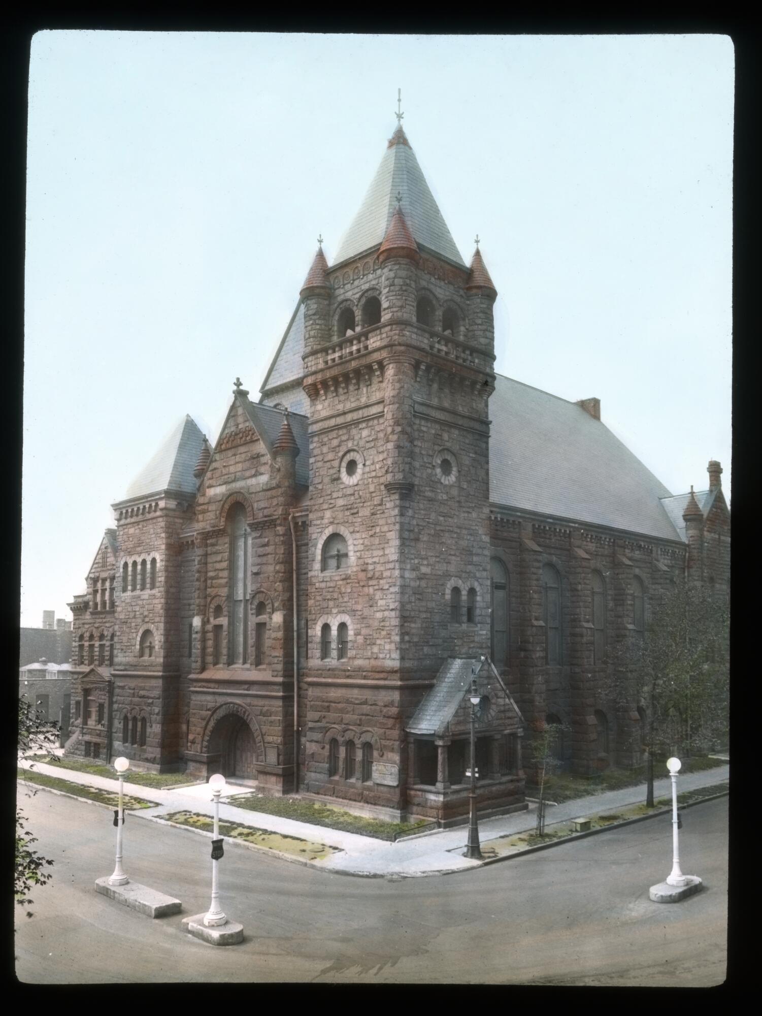 Large, multi-story stone church on a residential streetcorner.