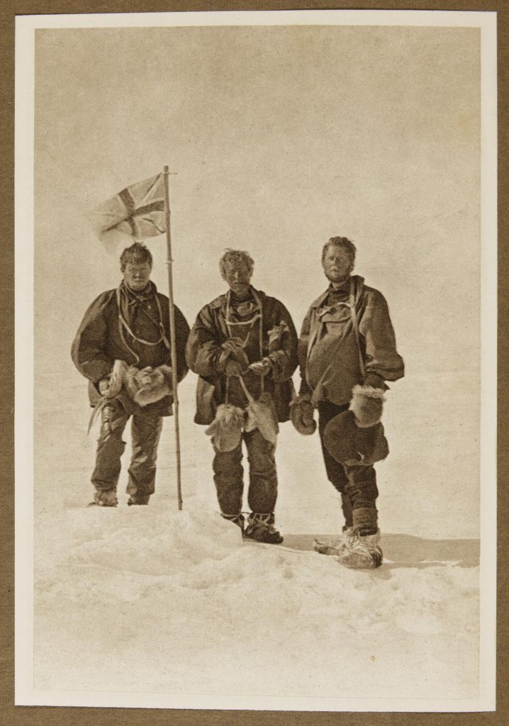 Image of three European men standing with a British flag in an expanse of snow.