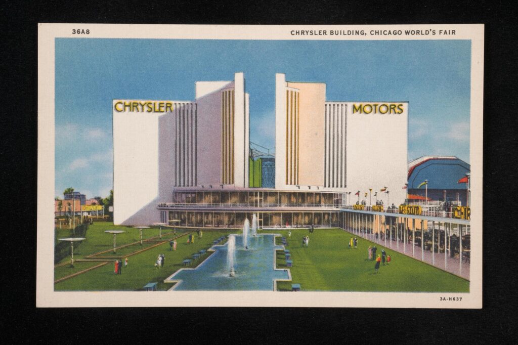Large white, black and yellow art deco building in front of a landscaped lawn with fountains. The building has a sign reading "Chrysler Motors"