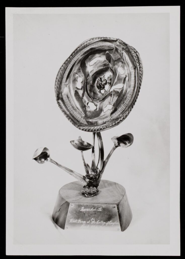 Black-and-white photograph of an award mounted on a small pedestal. It looks like an arrangement of flowers, but the small ones are twisted spoons, and the large one is a hubcap.